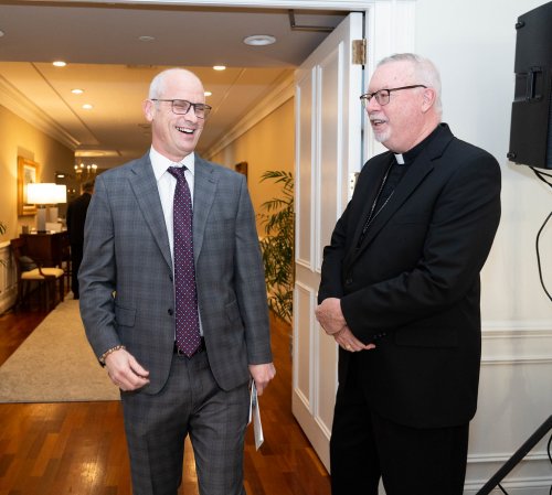 UConn Huskies head coach Dan Hurley smiling and laughing with Bishop Christopher Coyne.